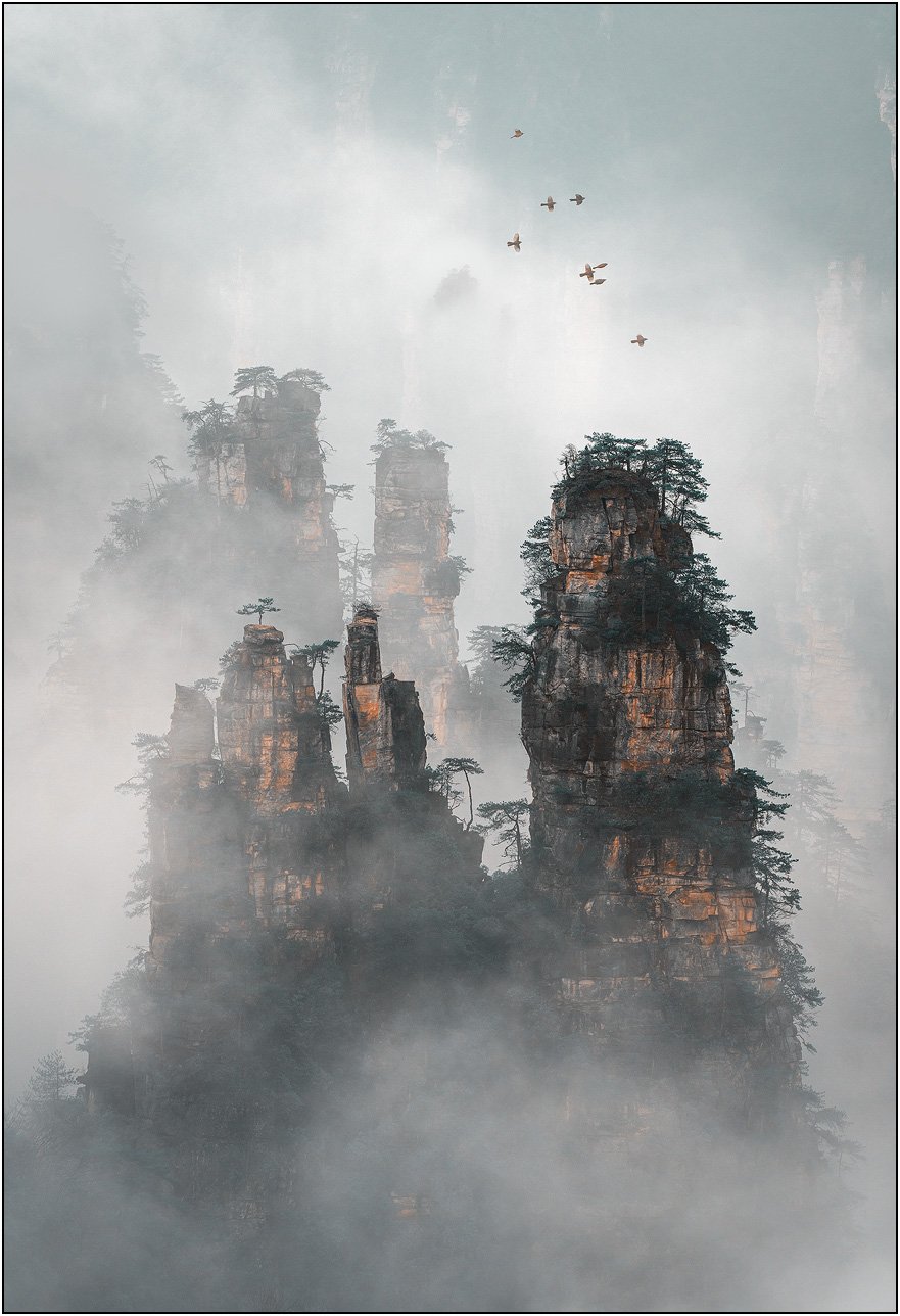 Sandstone mountains emerging through drifting mist and clouds in Zhangjiajie, China.