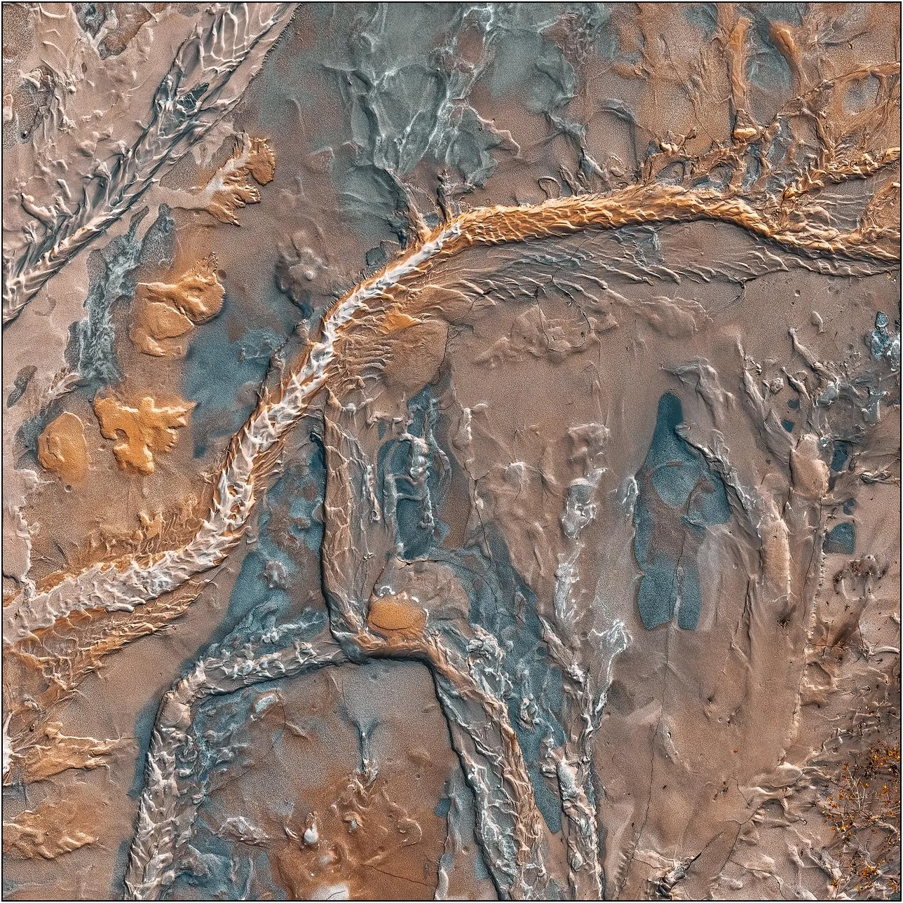 Aerial view of a tailings lake with layered mineral flows forming subtle abstract textures