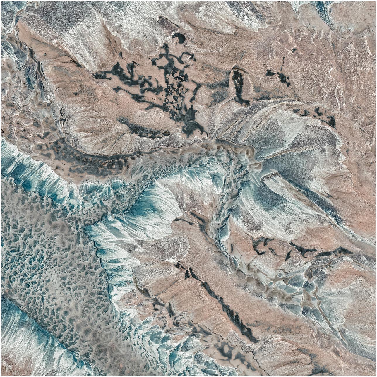 Aerial view of a tailings lake with flowing pale blue textures resembling frozen currents