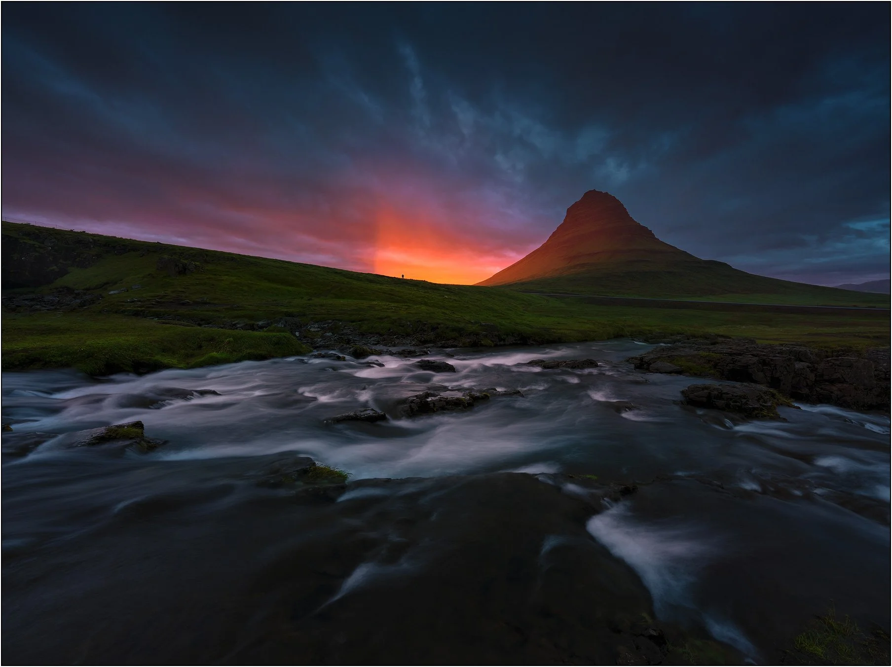 Sunset with glowing light at Kirkjufell, Iceland, long exposure of river flowing in the foreground.