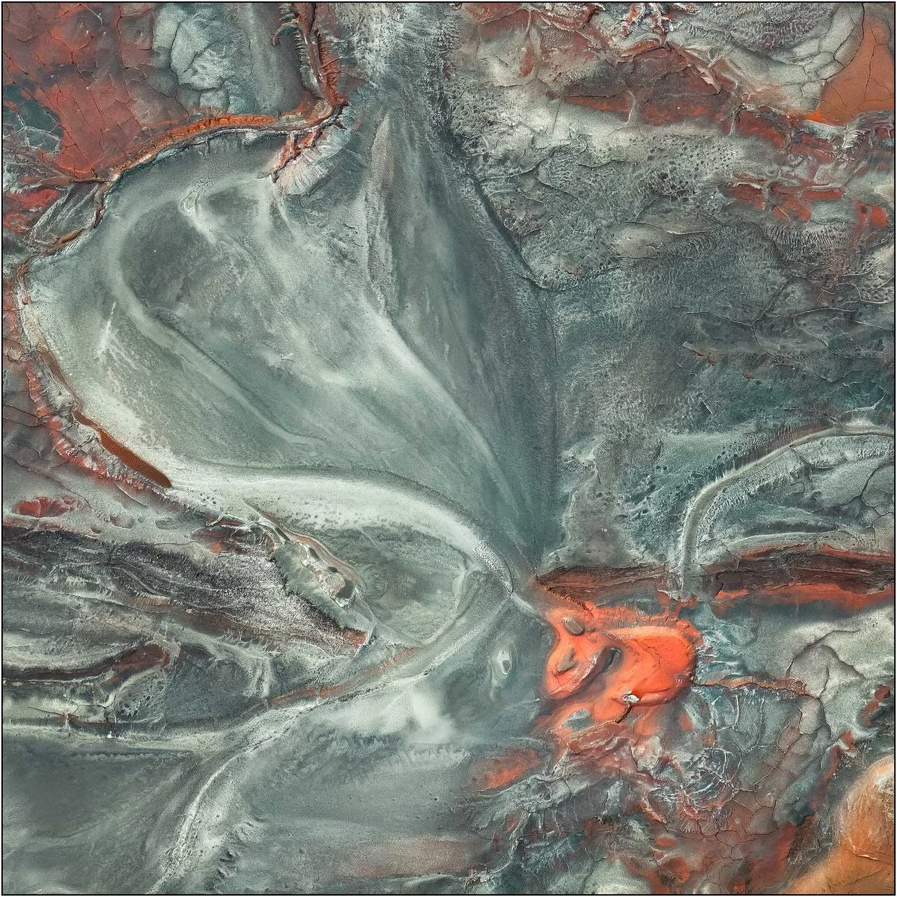 Aerial view of a tailings lake forming fan-like sediment patterns with subtle color transitions