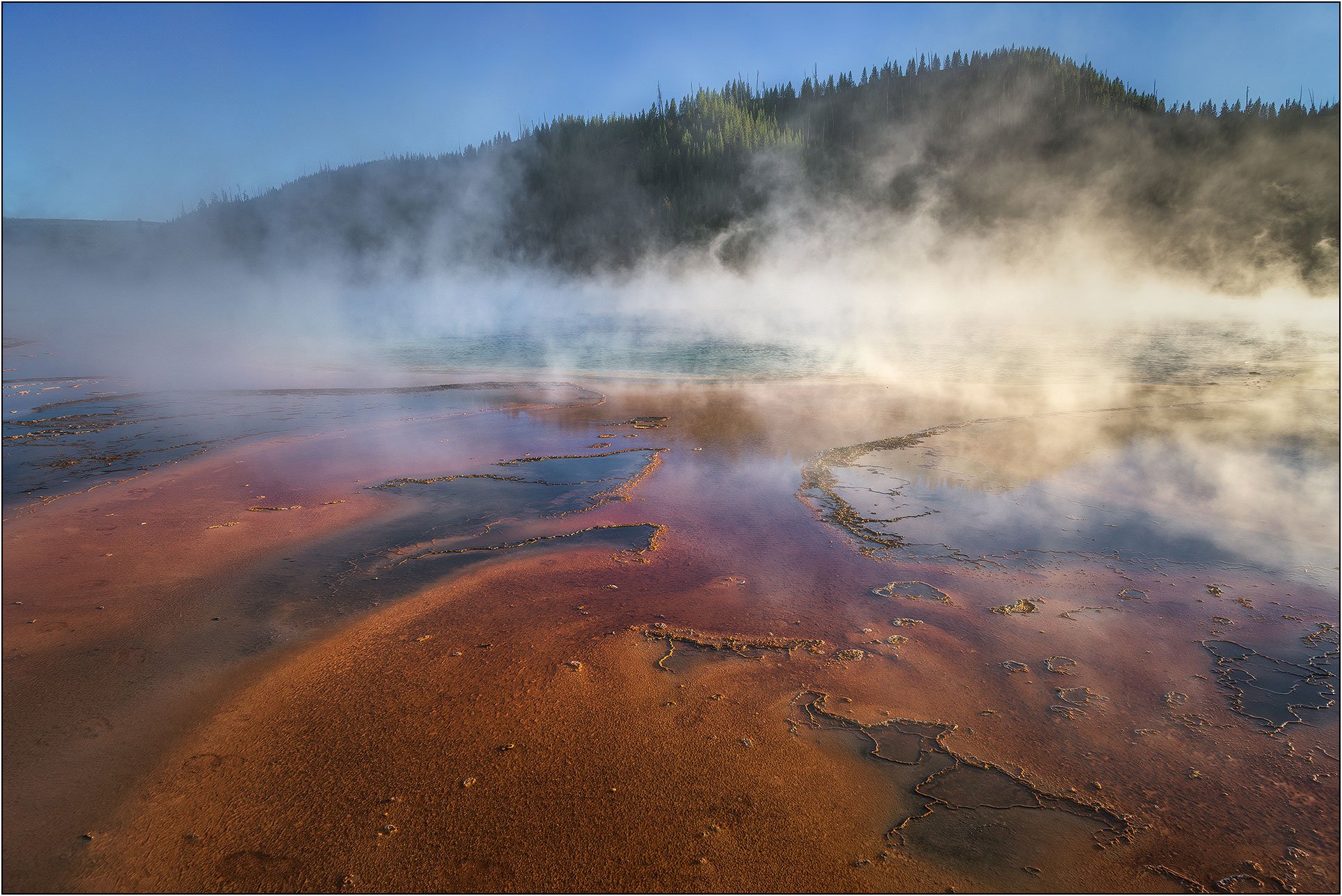 Colorful geothermal hot spring with steam rising in Yellowstone National Park