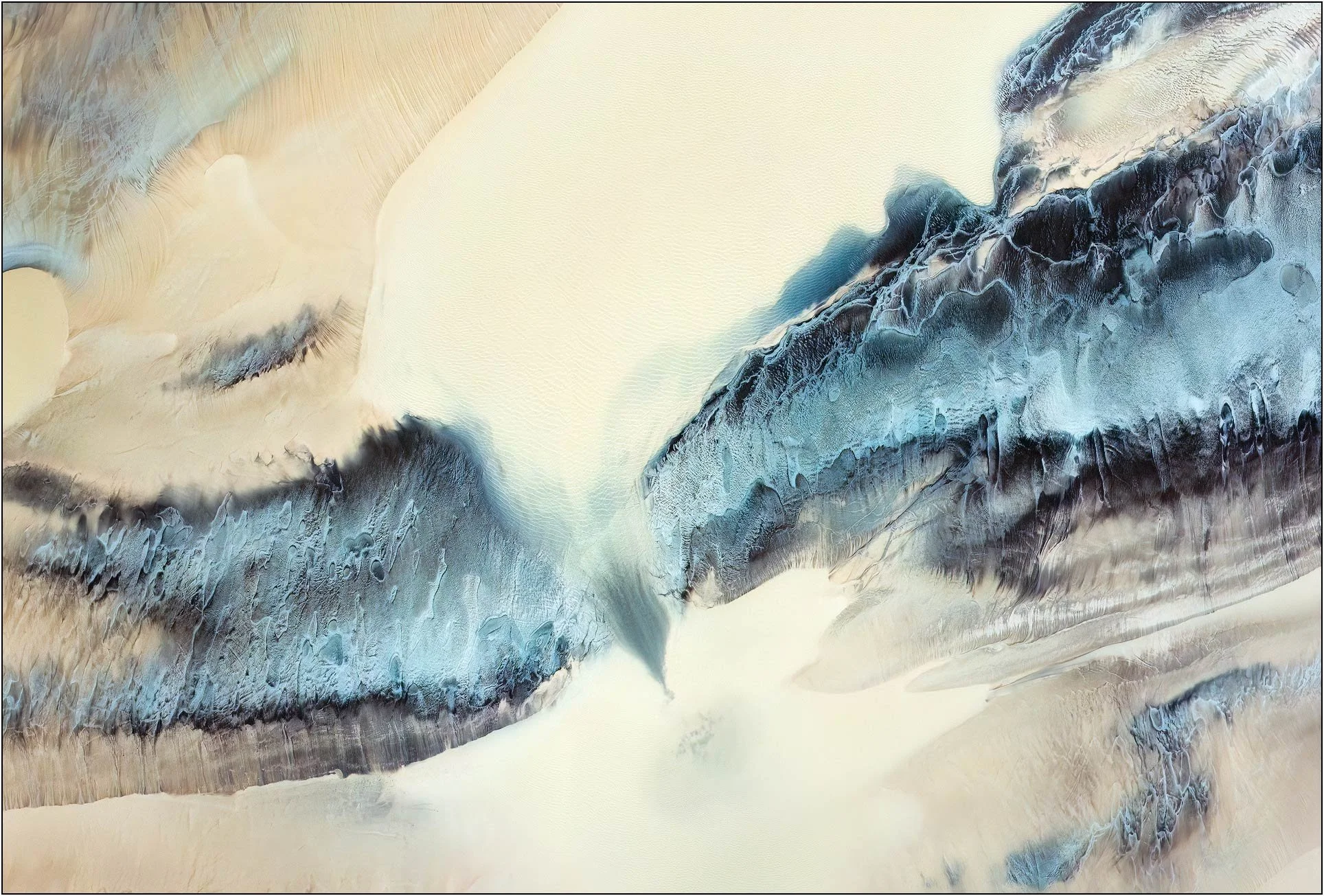 Fine art aerial photography of the Qiantang River tidal flats in China, where pale sand and blue-gray sediment form a serene abstract landscape. Sculpted by tidal currents, the flowing contours evoke mountains, glaciers, and mist, transforming the ri