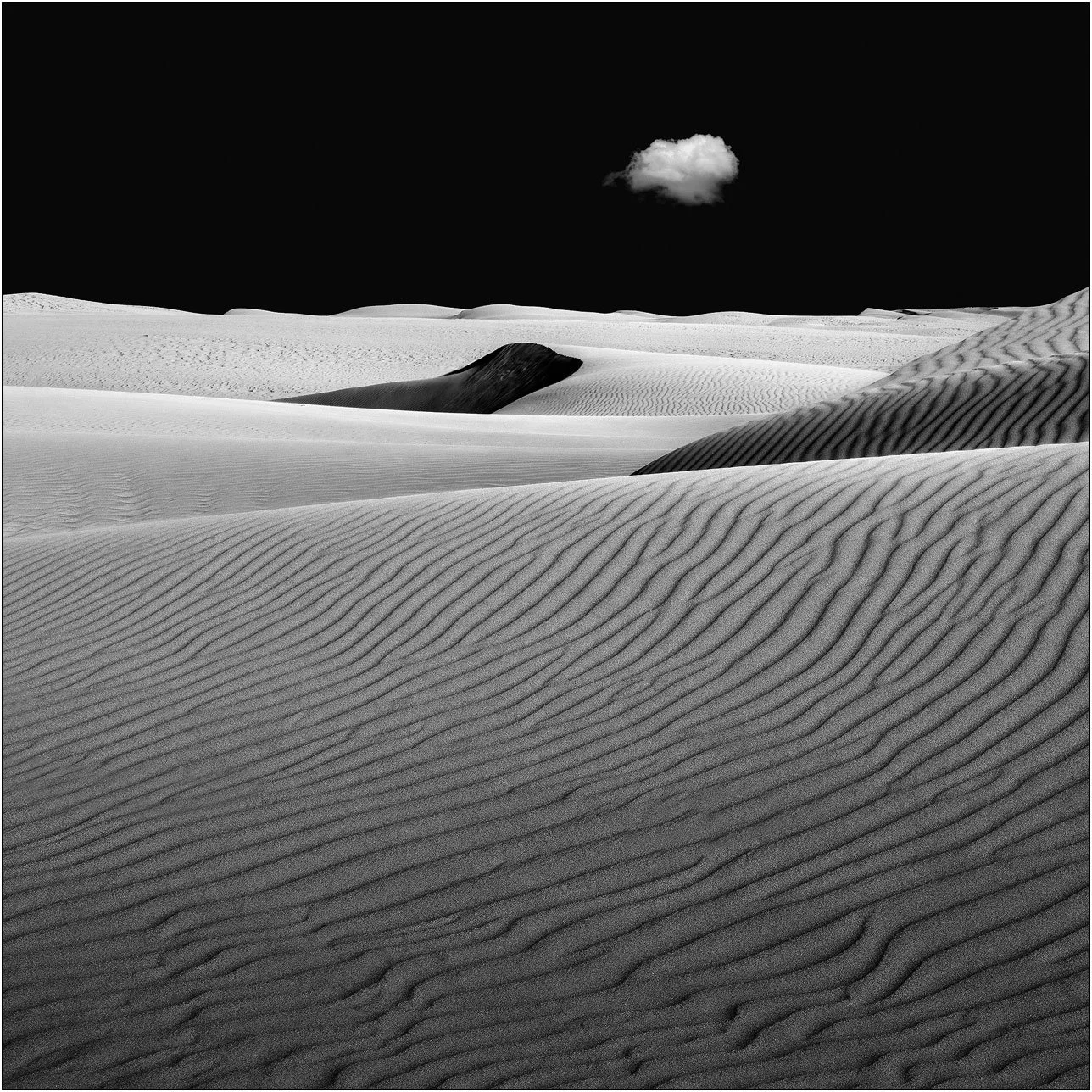 Abstract sand dunes with a lone cloud in a minimalist black sky