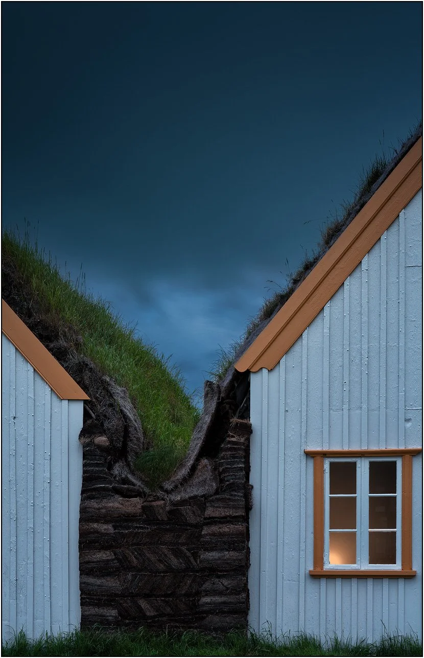 Grass covered houses at Glaumbær Farm, Iceland, with orange colored roof and window.