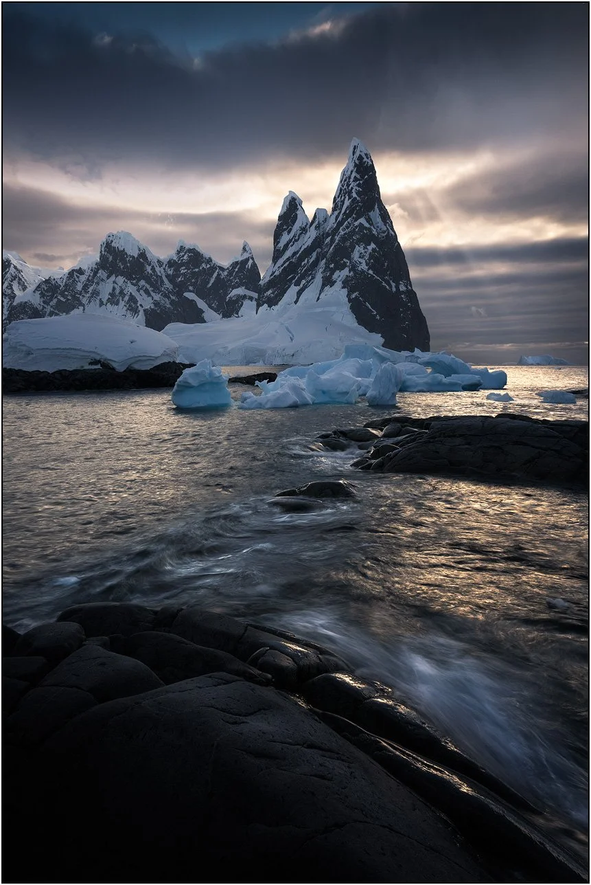 Slow shutter photograph of mountain and wave actions during sunset in Antarctica peninsula.