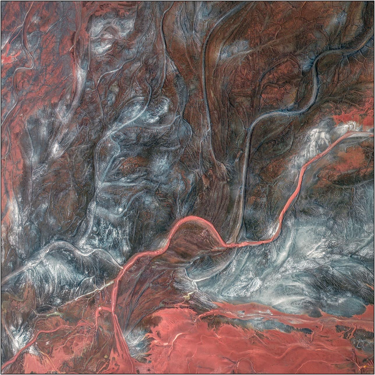 Aerial view of a tailings lake with intricate channels forming a network of flowing textures