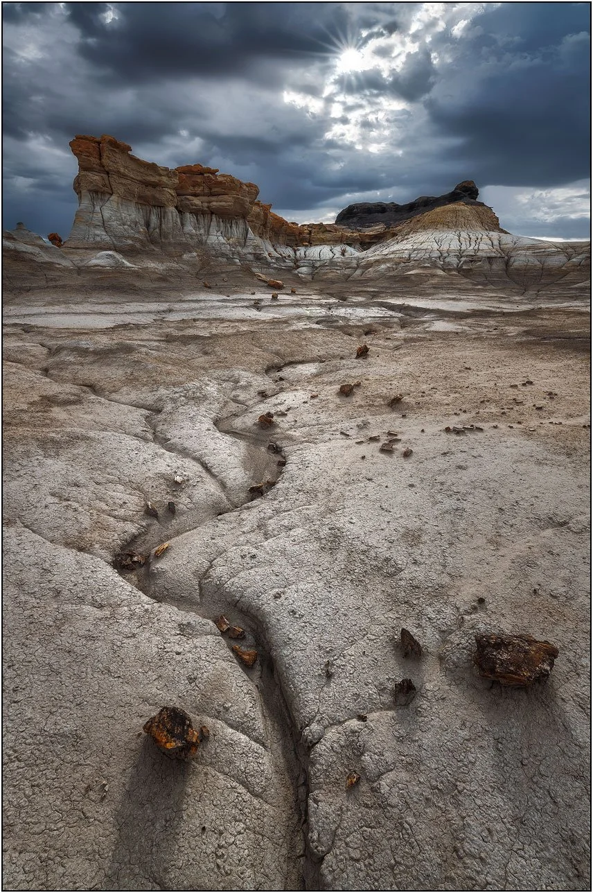 Eroded badlands terrain with cracked textures and scattered rocks