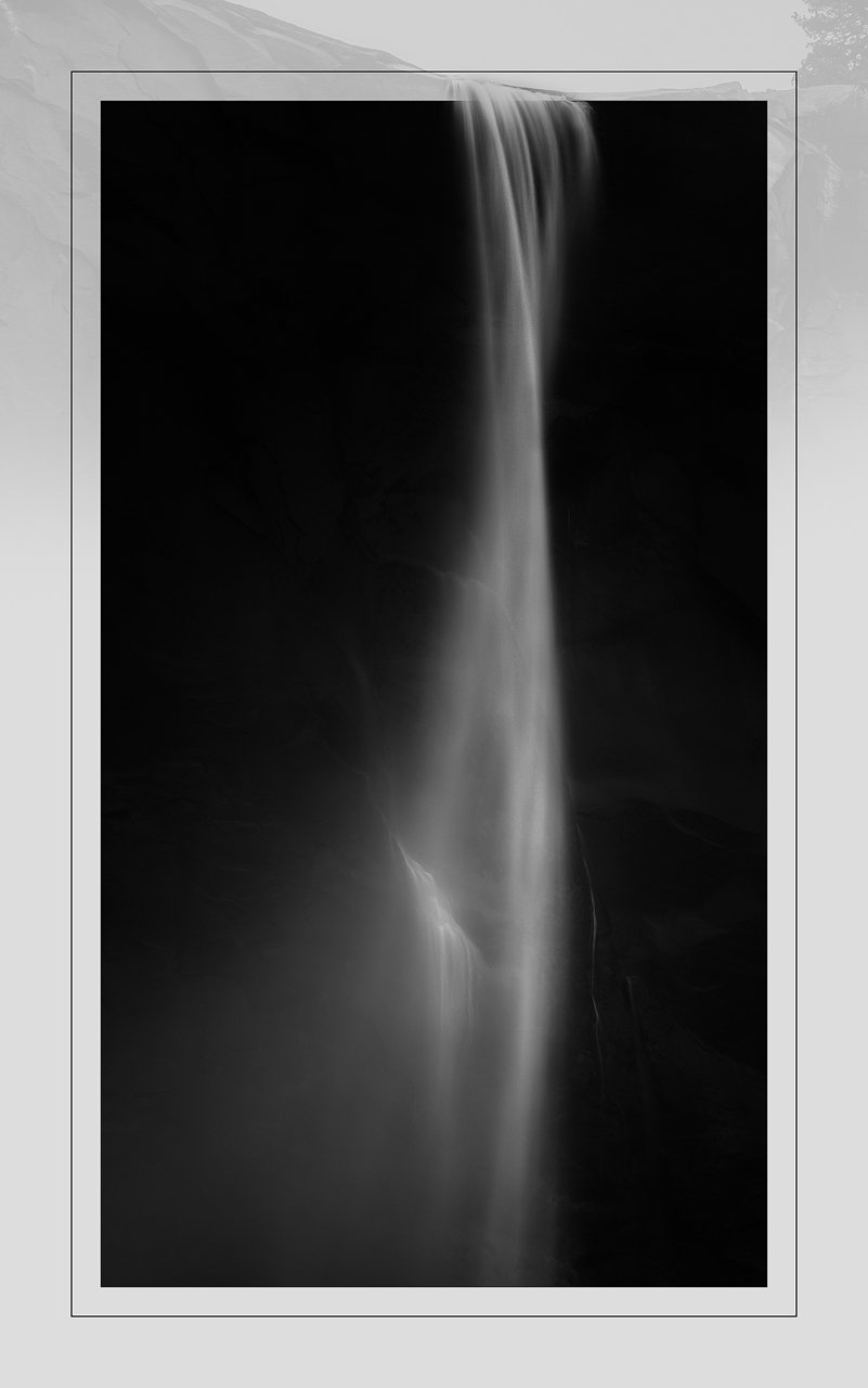 Minimalist black and white image of a waterfall descending through darkness in soft flowing motion, Yosemite national park, California.