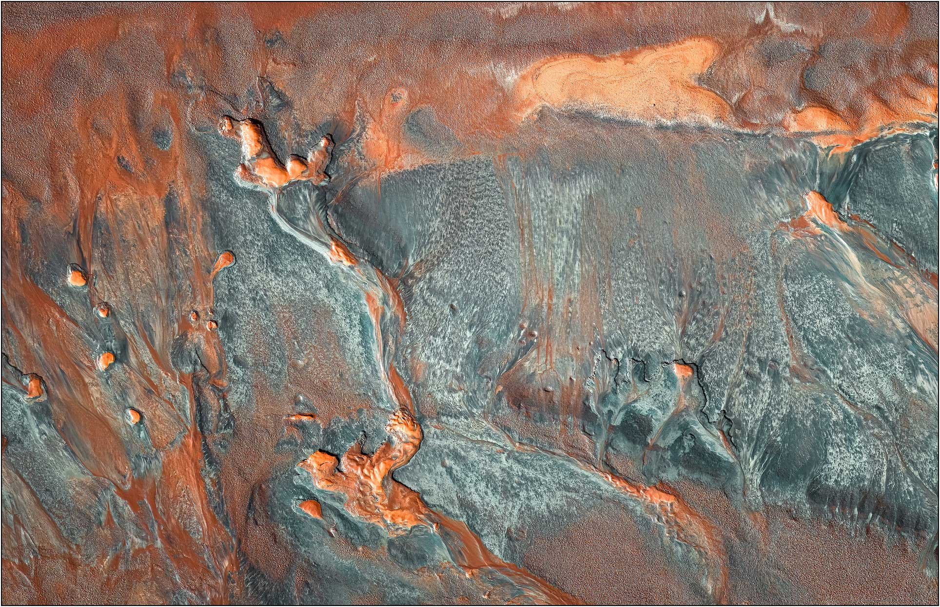Aerial view of a tailings lake with branching mineral flows in rust and teal tones
