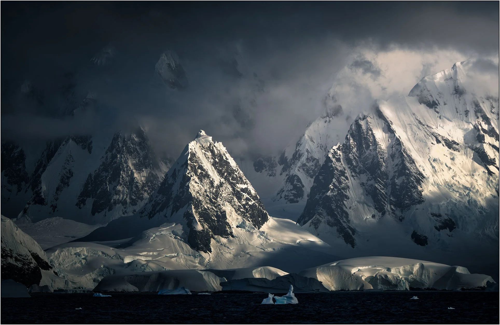 The striking peaks of Antarctica peninsula under dramatic light.
