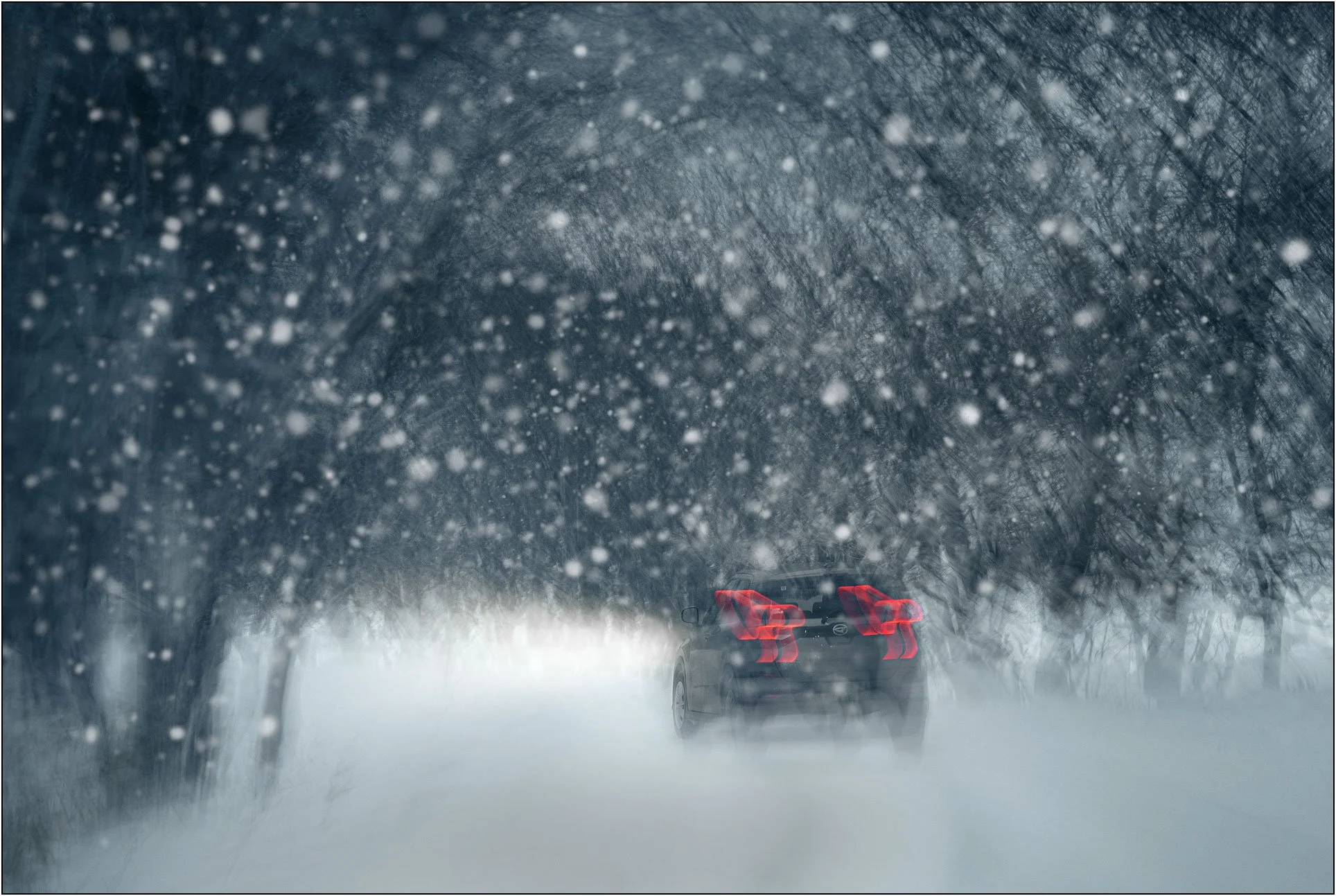 A car driving through a snowstorm with glowing red taillights in a forest road in Hokkaido, Japan.