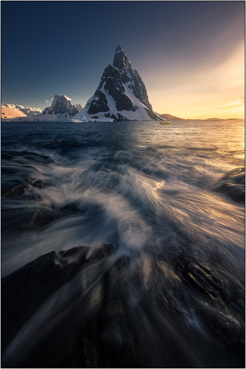 Slow shutter photograph of mountain and wave actions during sunset in Antarctica peninsula.
