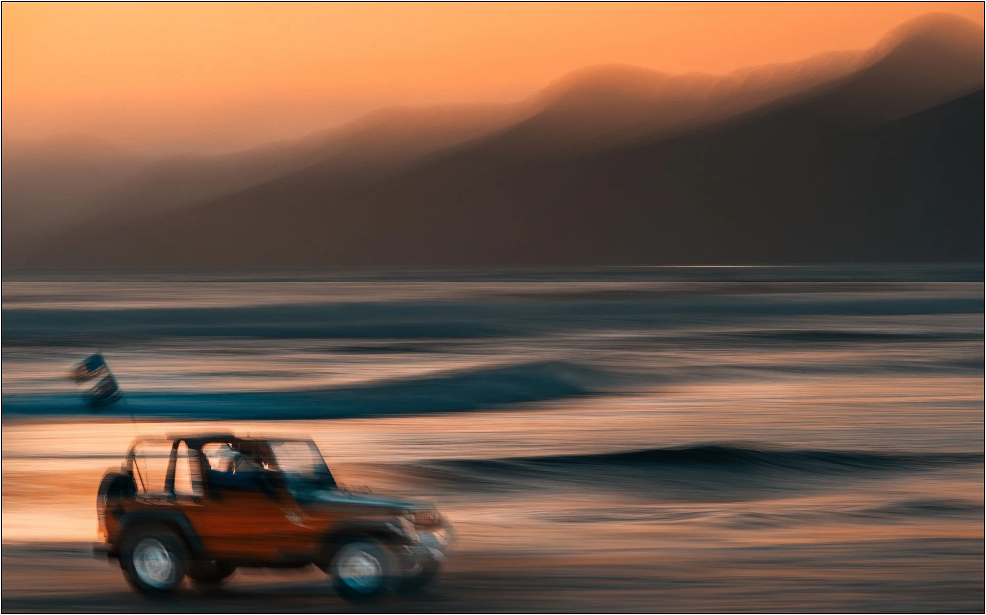Blurred off-road vehicle moving along the beach at dusk, Pismo beach, California