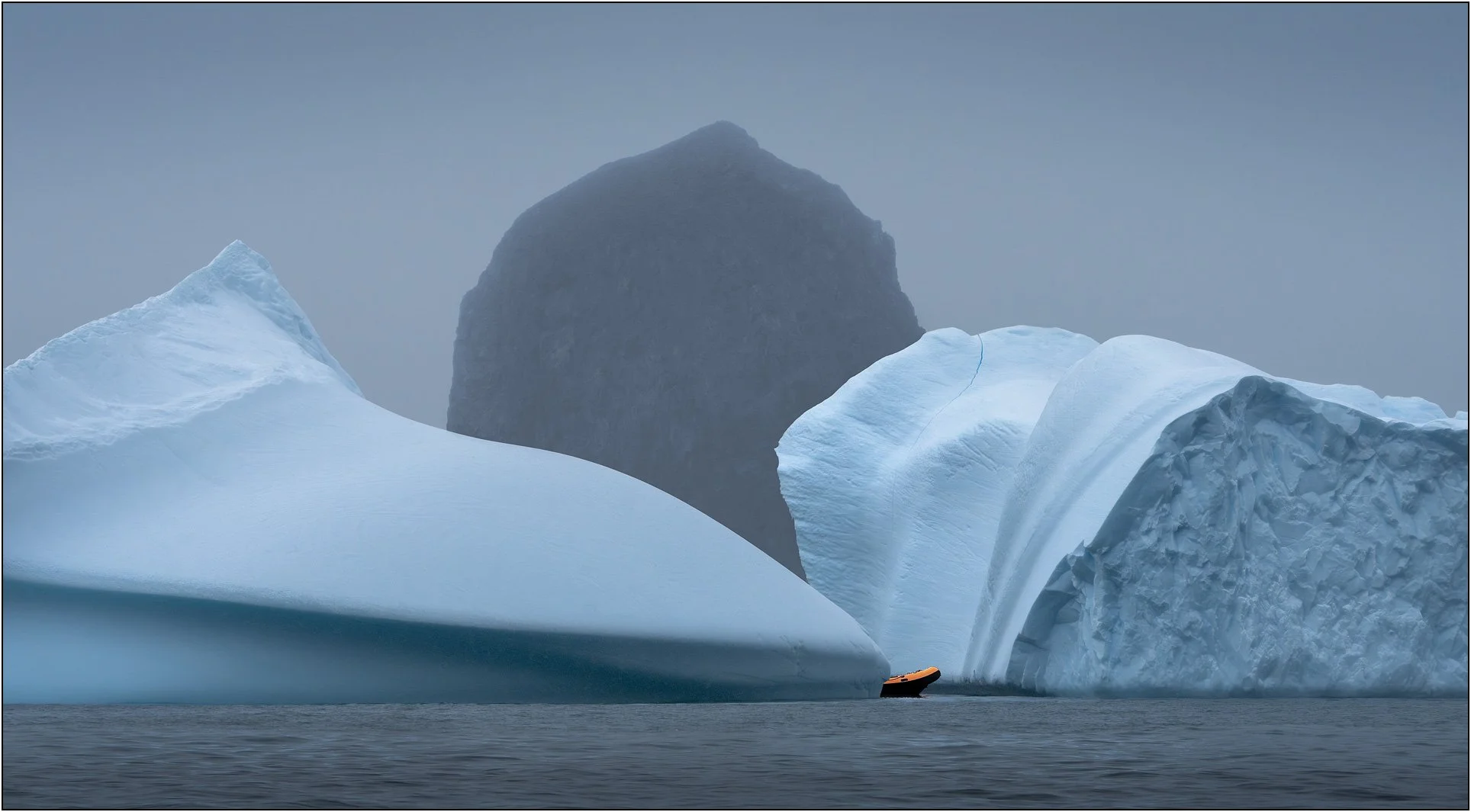 Icebergs and part of a zodiac and a mountain in Antarctica.