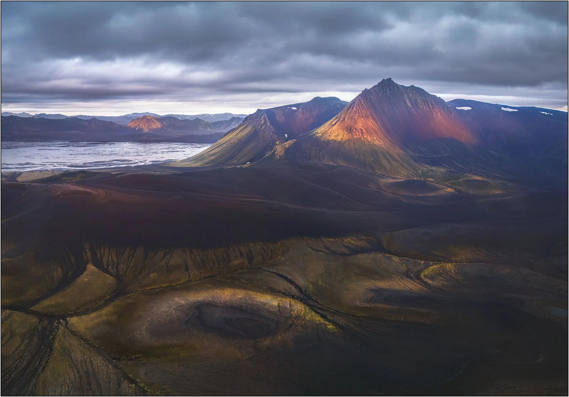 Aerial view of highland Iceland landscape with mountains, craters, and glacier river.