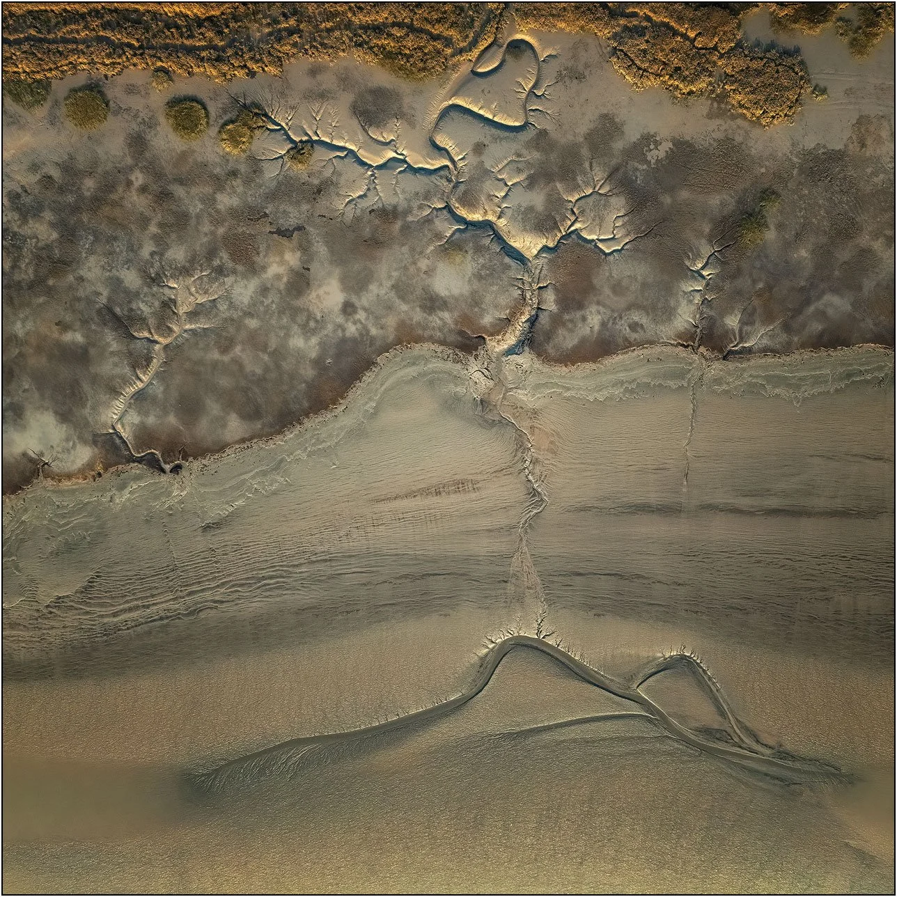 Aerial abstraction of tidal patterns with layered textures and flowing sediment forms