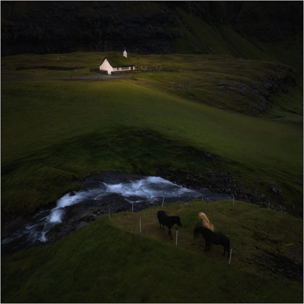 Saksun church in Faroe Islands, with some horses and flowing water.