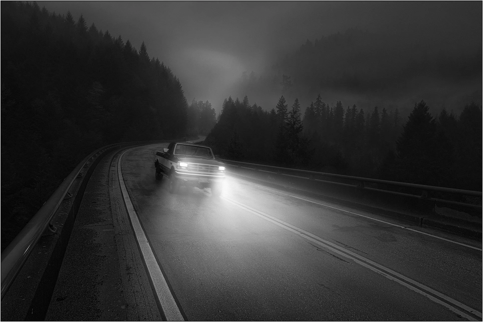 Car driving on a foggy mountain road at night