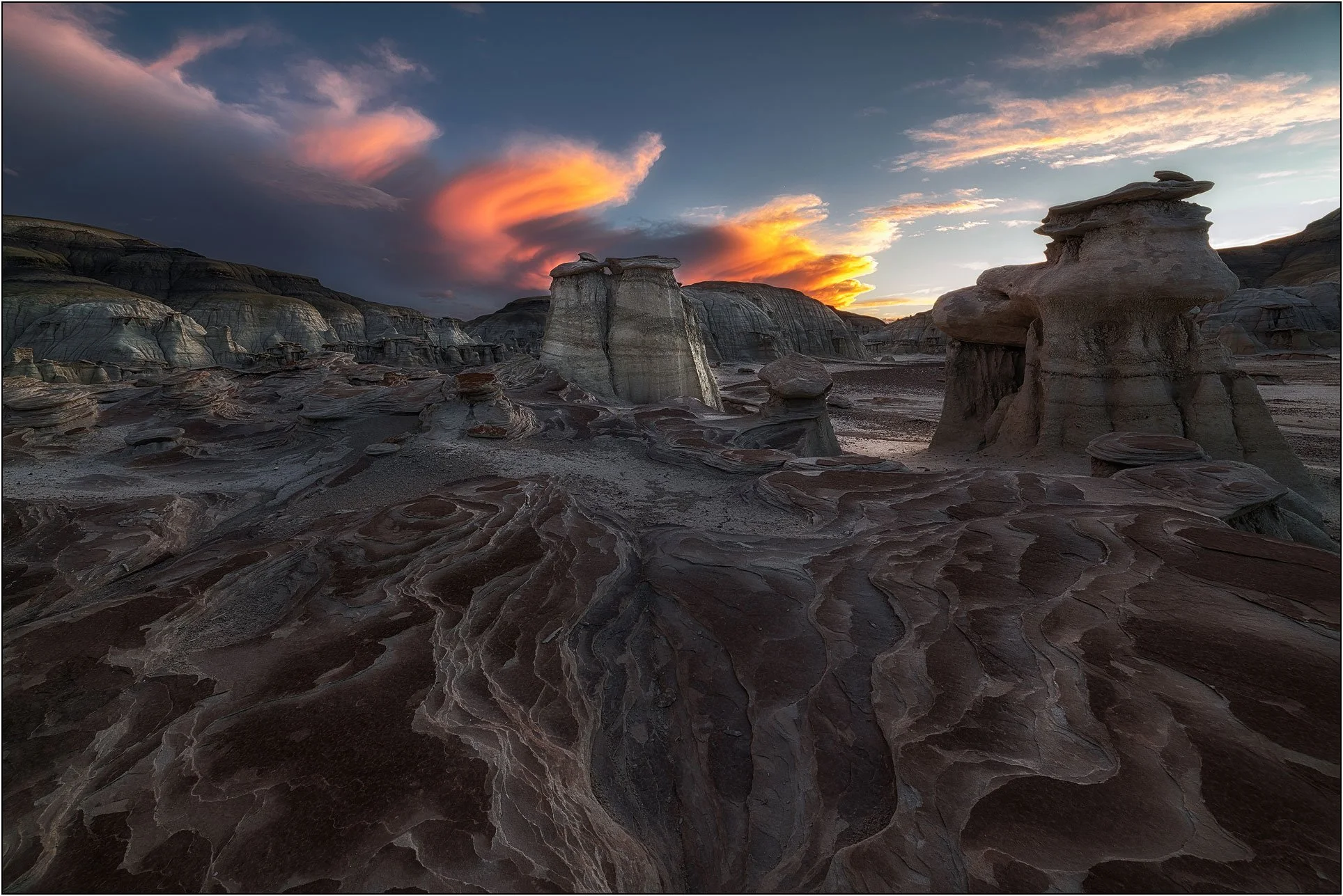 Rock formations with textured foreground under dramatic sunset clouds