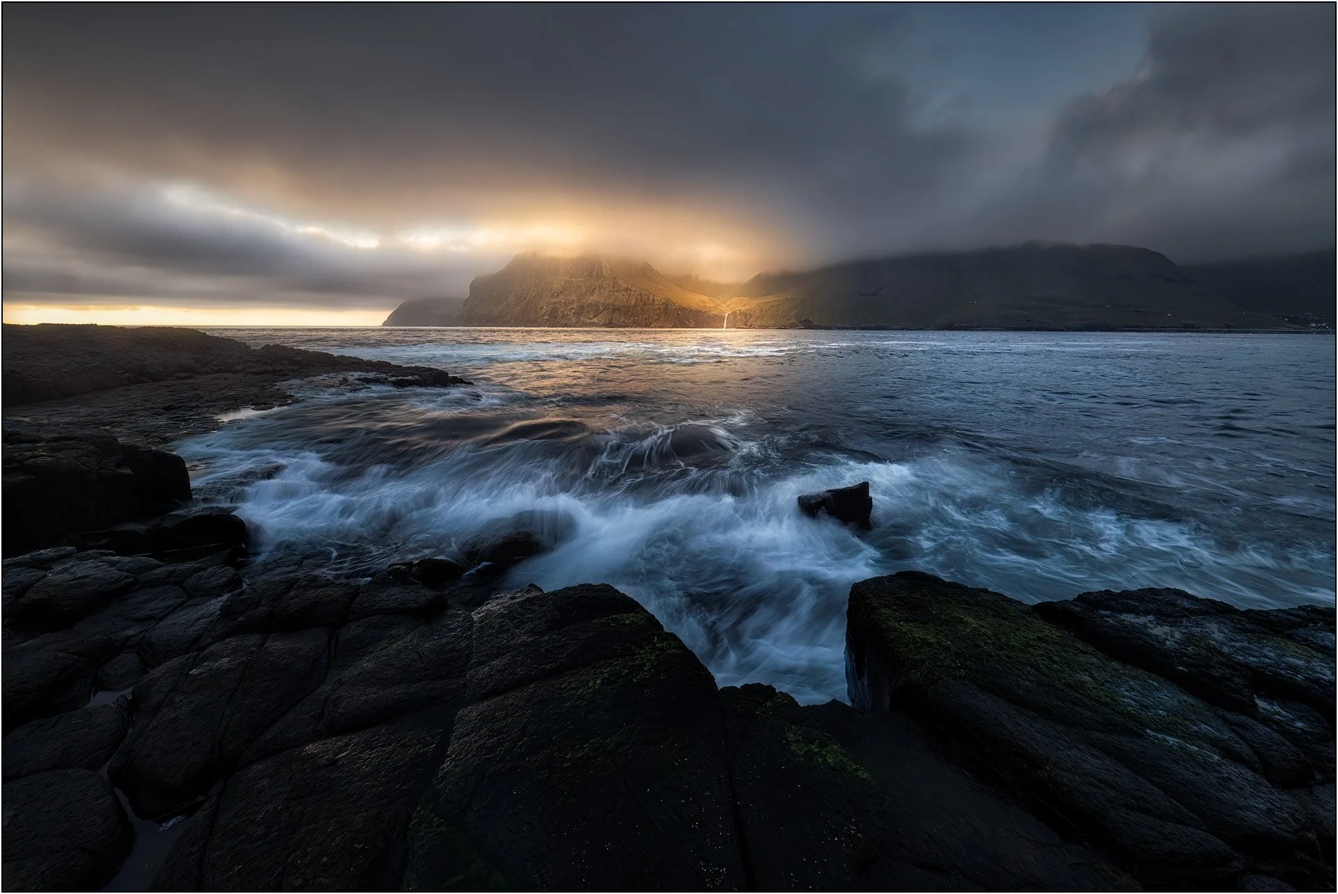 Waves crushing on island of Drangarnir, Faroe Islands, with sunset clouds, golden light and sea stacks.