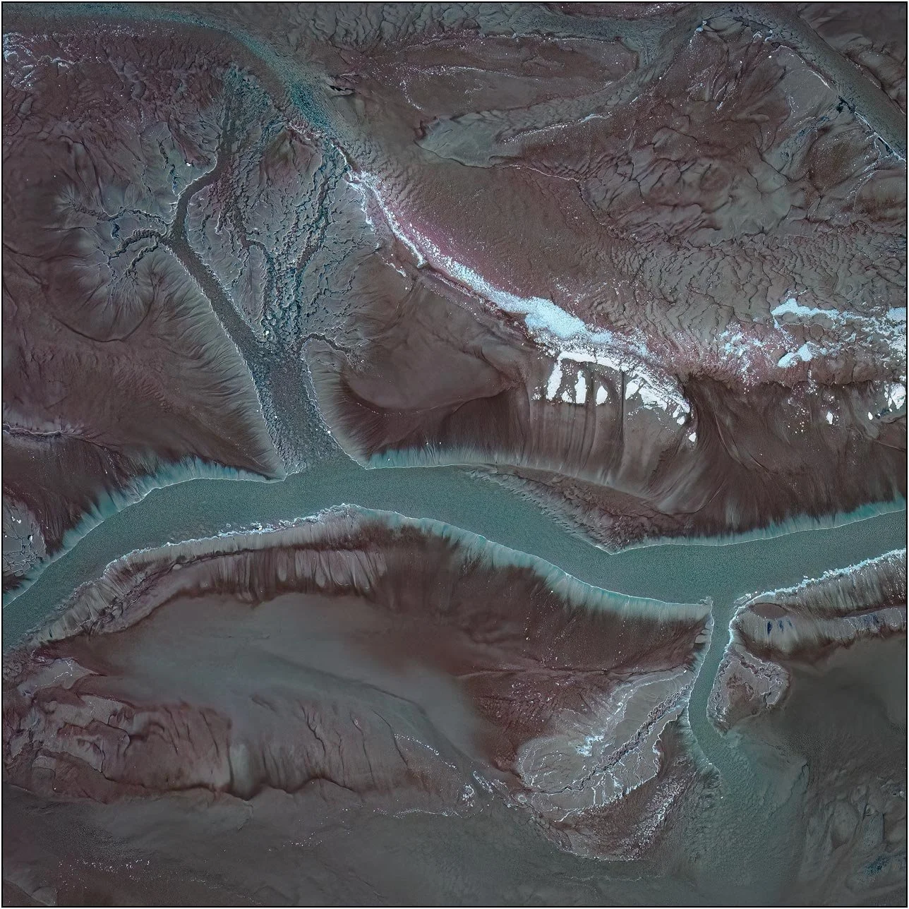 Aerial view of a tailings lake with branching channels flowing into a central waterway