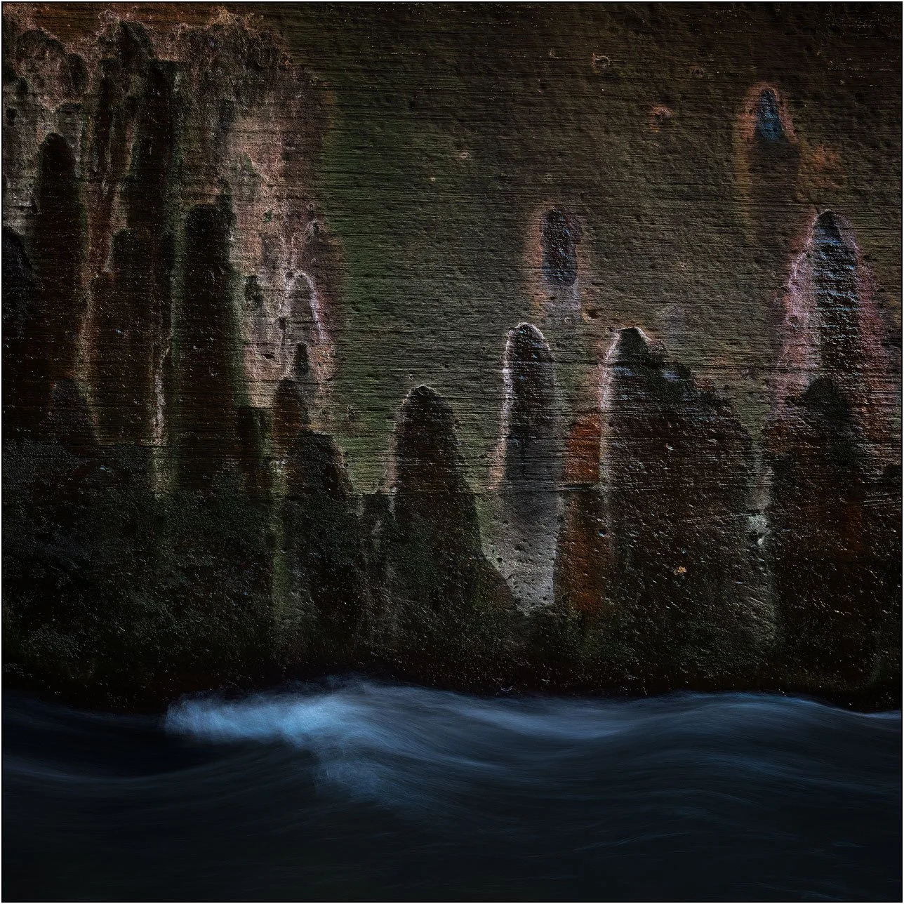 Eroded canyon wall with textured rock formations and flowing water in Zion Narrows
