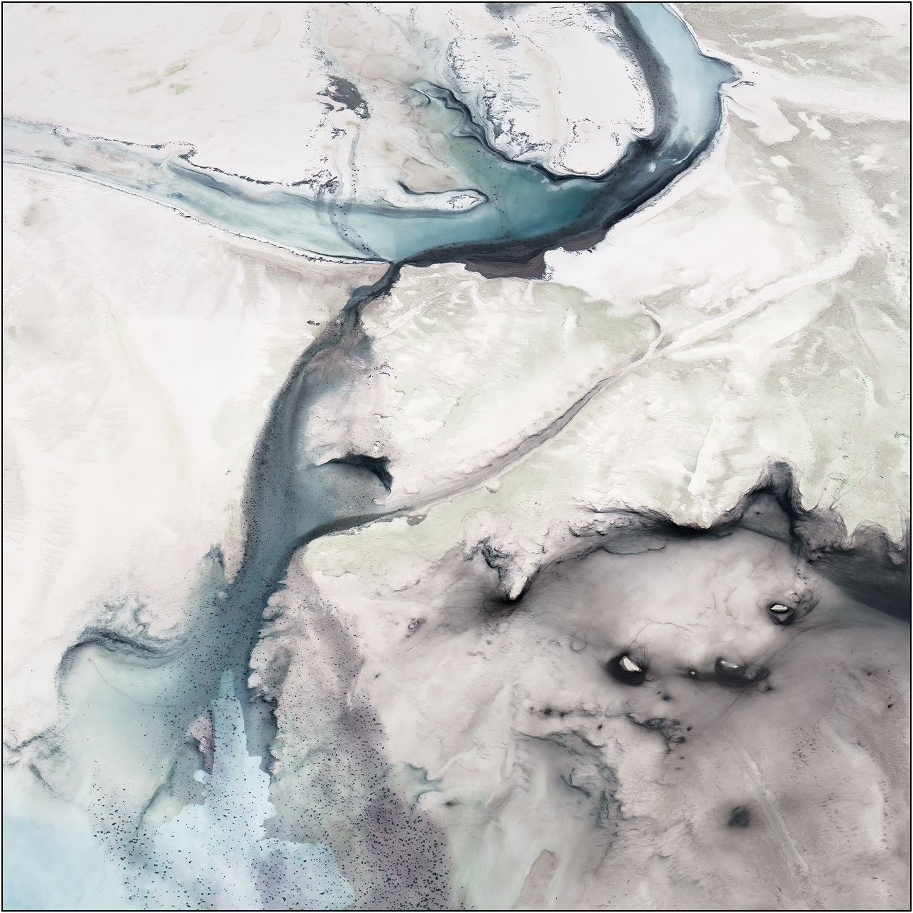 Aerial abstraction with soft blue channels flowing through a pale textured landscape