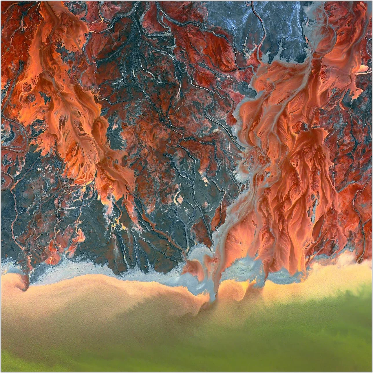 Aerial view of a tailings lake with swirling pale deposits merging into a soft shoreline
