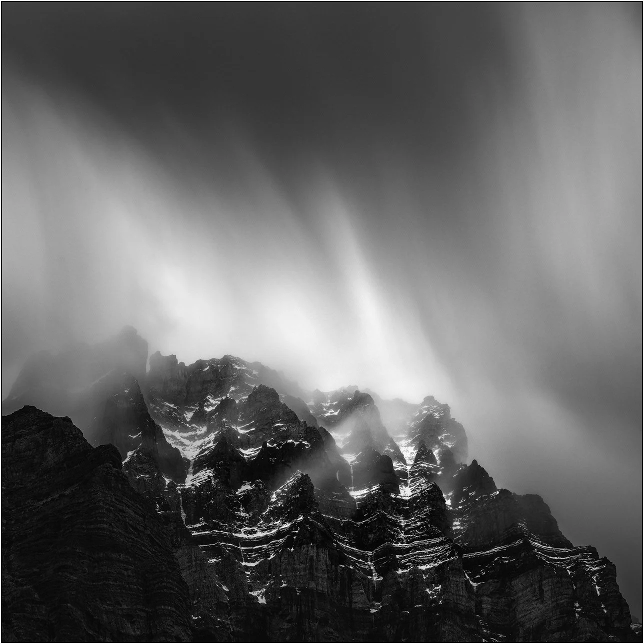 Black and white long exposure photograph of cloud and peaks of the Canadian Rockies.