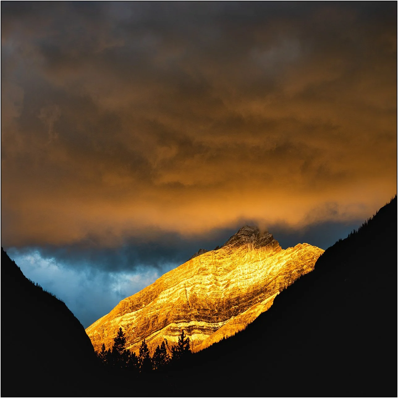 Cloud and peaks of the Canadian Rockies at sunrise with golden light.