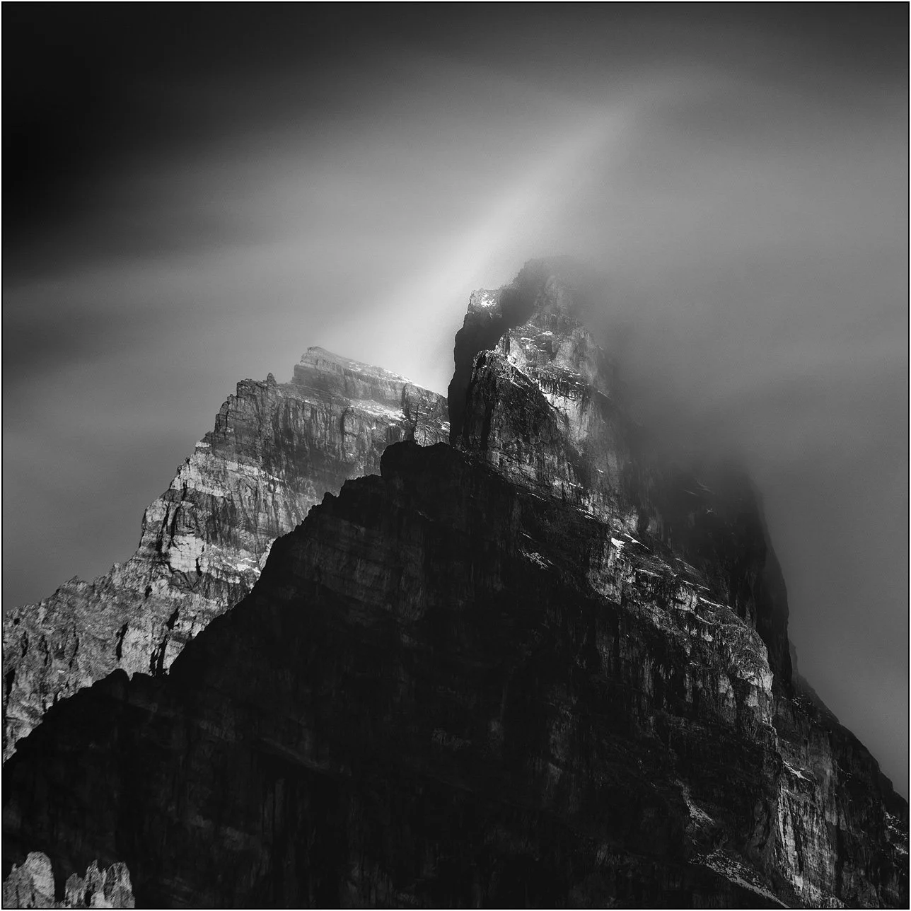 Black and white long exposure photograph of cloud and peaks of the Canadian Rockies.
