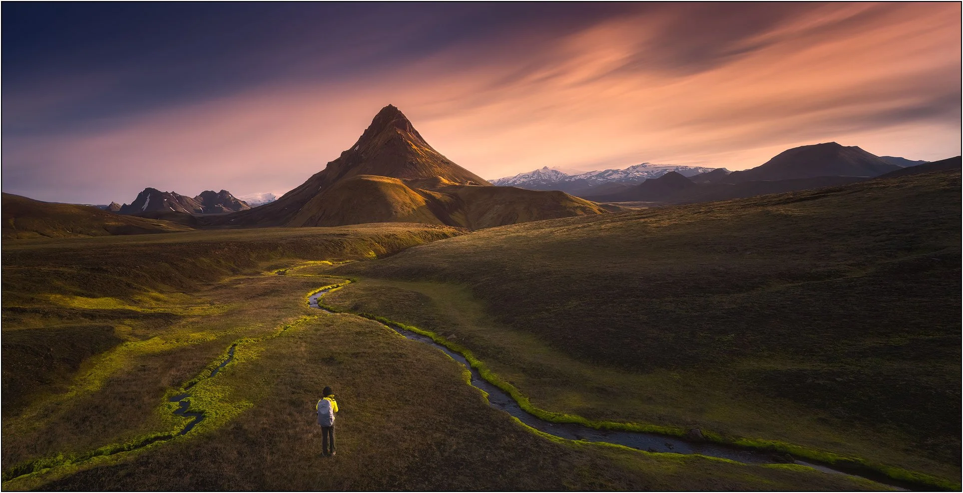 A woman with backpack exploring hightland Iceland landscape with mountains and rivers.