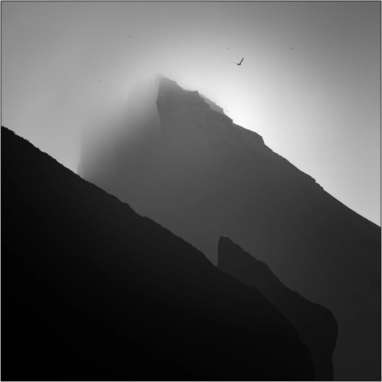 Black and white silhouette misty cliffs of Drangarnir, Faroe Islands.
