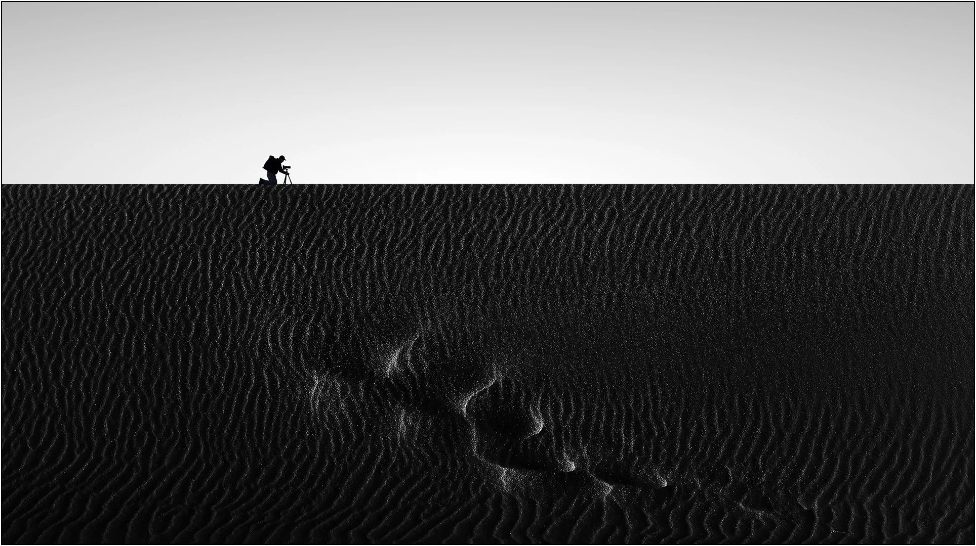 Minimalist sand texture with a lone photographer on the horizon