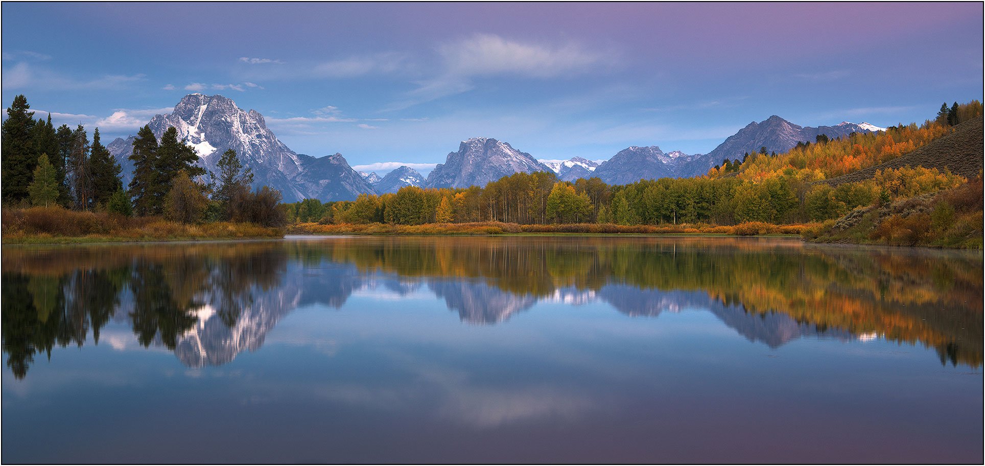 Autumn colors reflecting in Snake River with Teton Range mountains in Grand Teton National Park