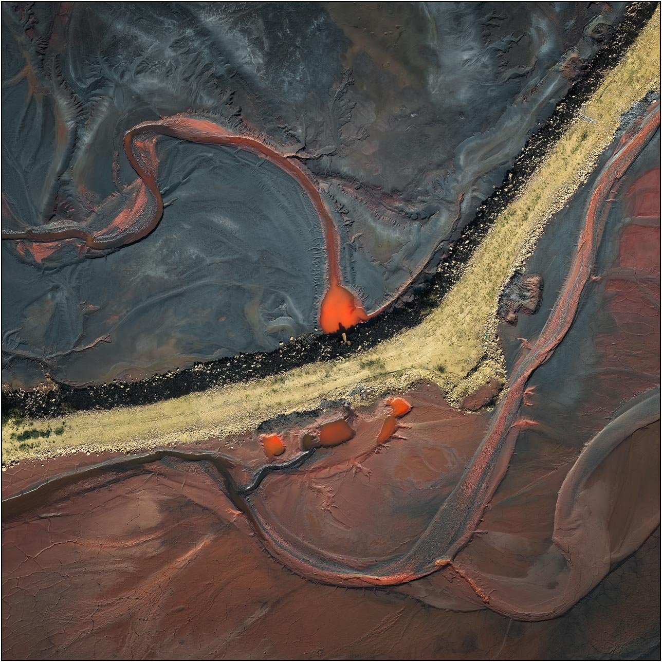 Aerial view of a tailings lake with a curved red flow meeting a textured embankment