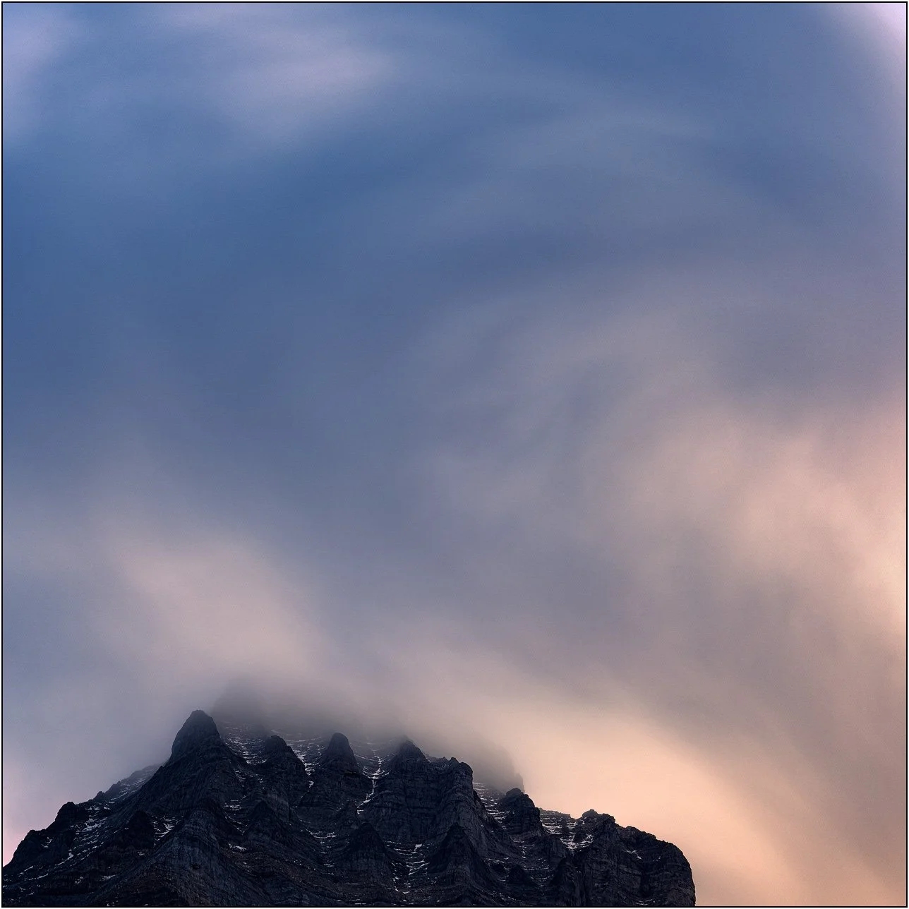 Long exposure photograph of cloud and peaks of the Canadian Rockies.