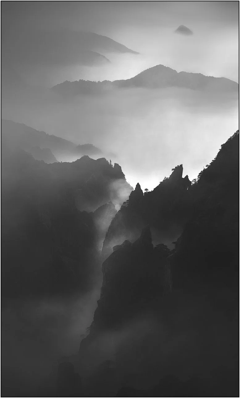Mountains emerging through drifting mist and clouds in Huangshan, China.