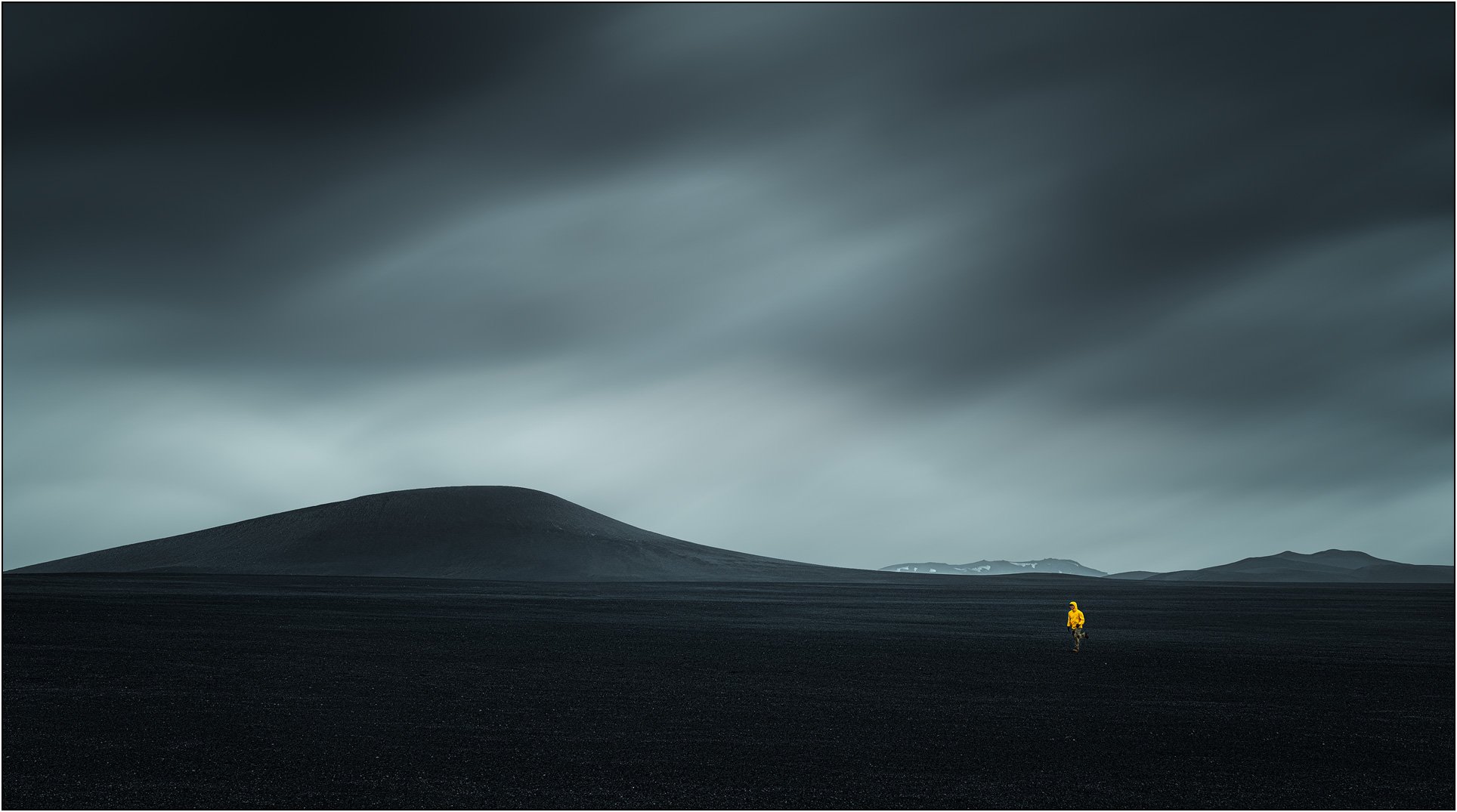 Man in yellow jacket running on black desert of Iceland highland.
