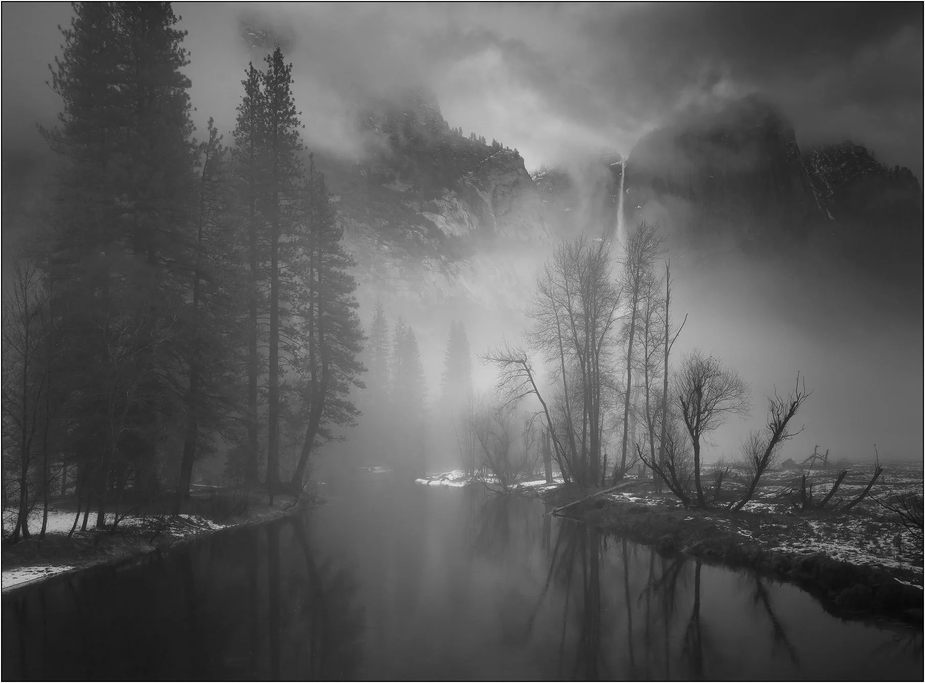 Foggy river and trees with waterfall in background in Yosemite National Park