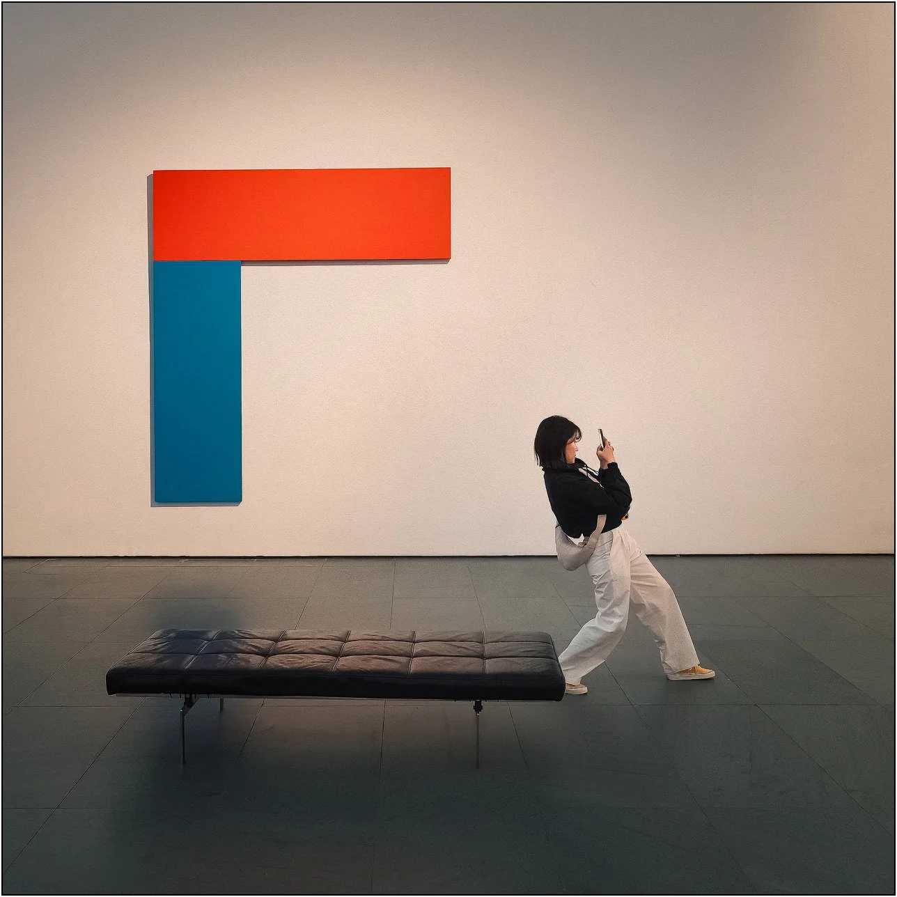 Minimalist museum scene with bold geometric artwork and a person photographing it