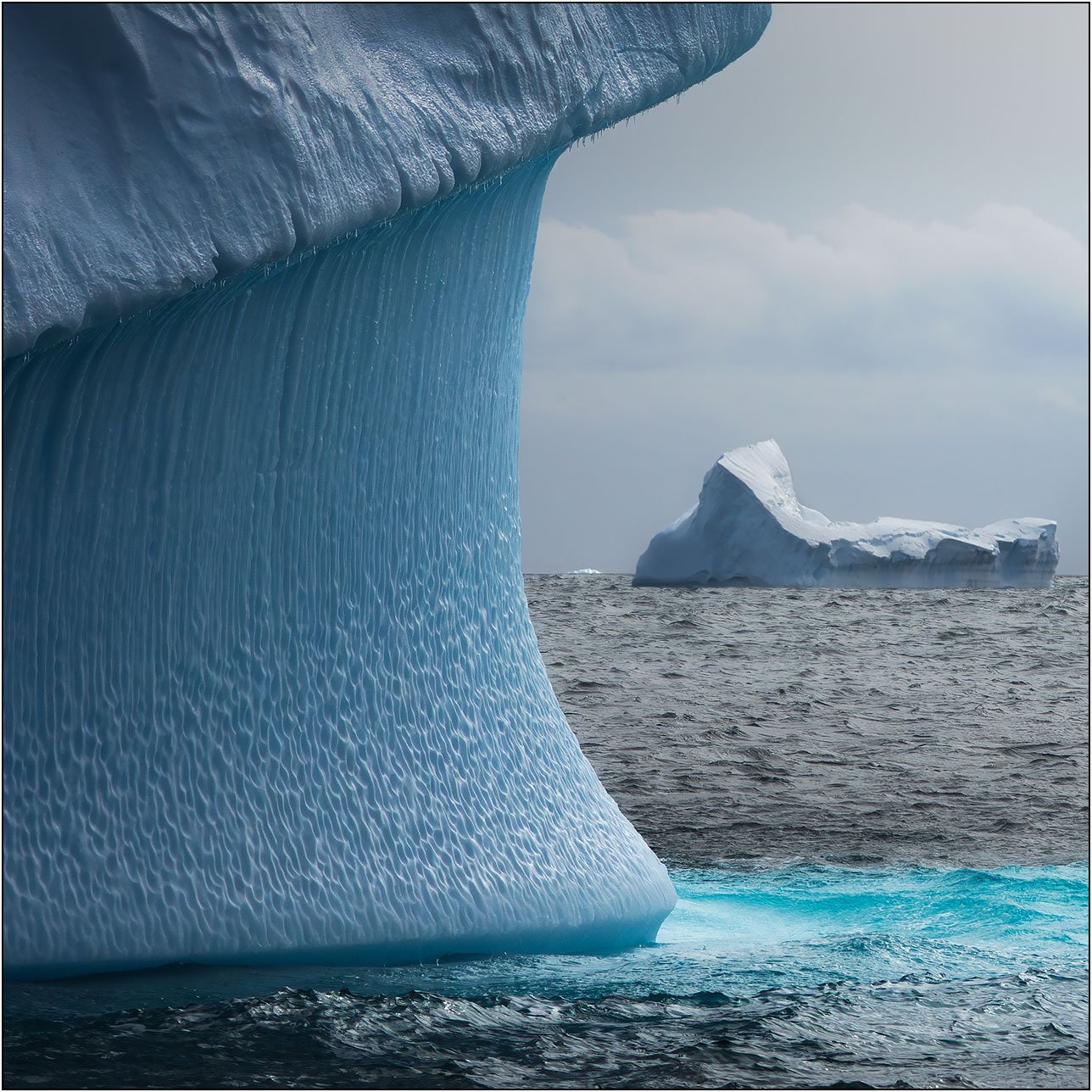 Icebergs with detailed ice textures floating in the southern ocean in Antarctica.
