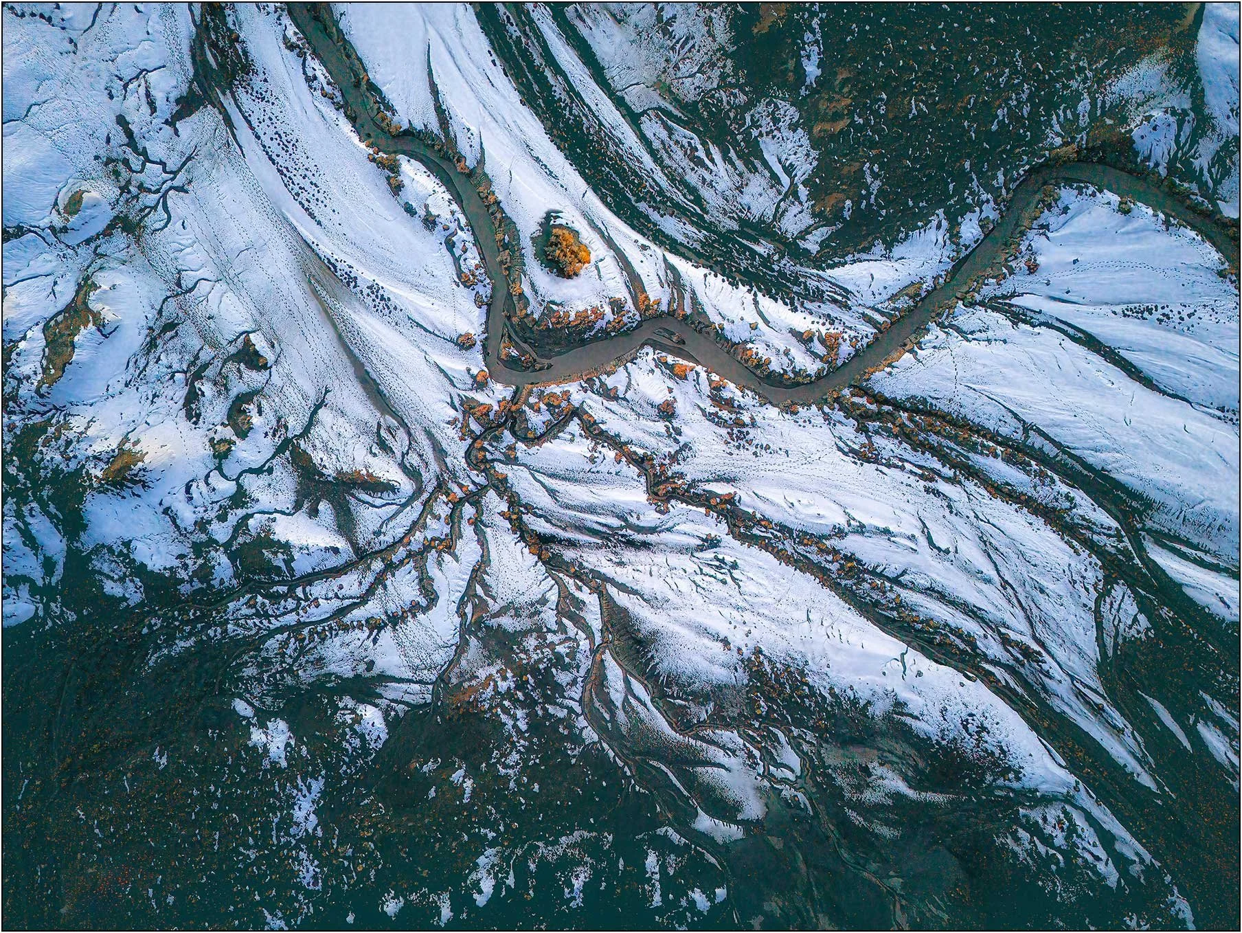 Aerial view of snow-covered badlands with branching river channels
