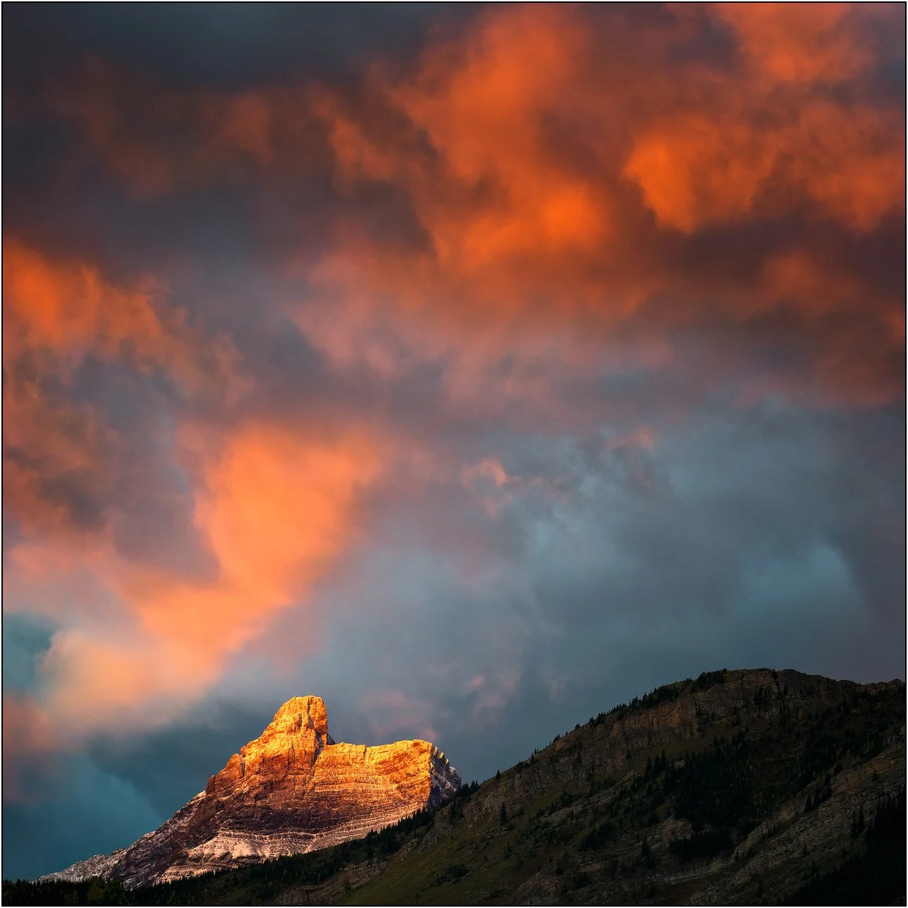 Cloud and peaks of the Canadian Rockies at sunrise with golden light.