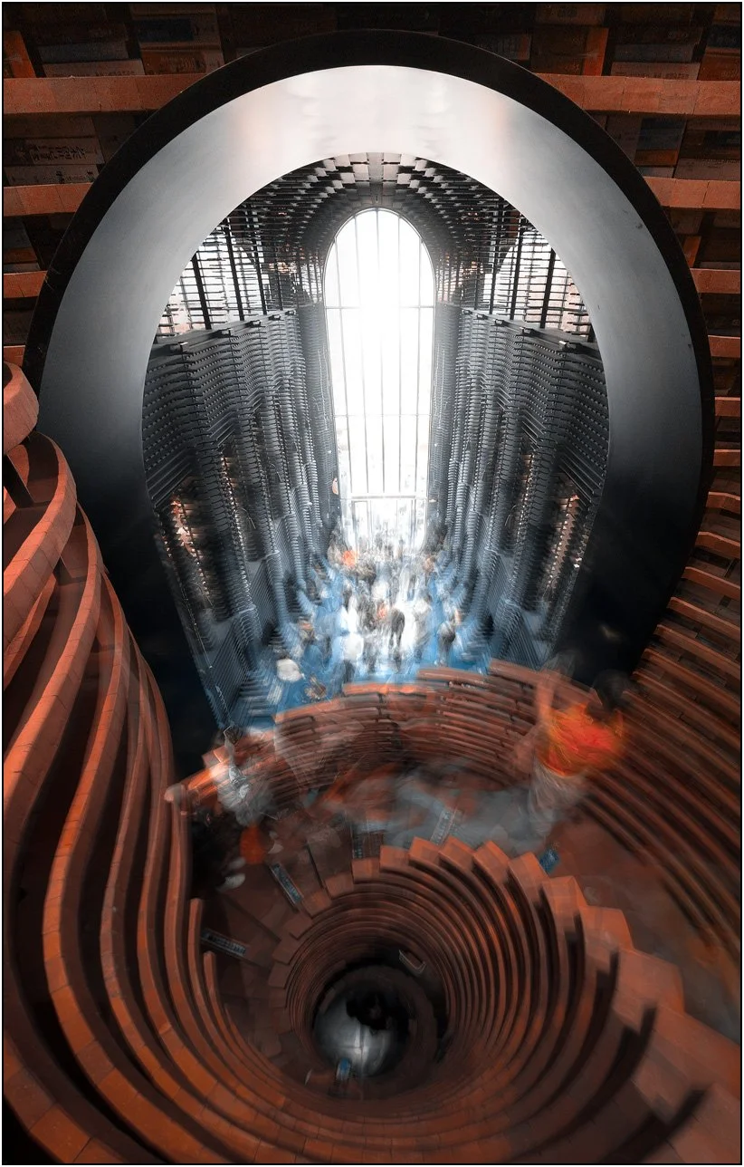 Spiral staircase inside Zhongshuge bookstore in Tianjin, China, with motion blur of people, creating a dynamic architectural scene