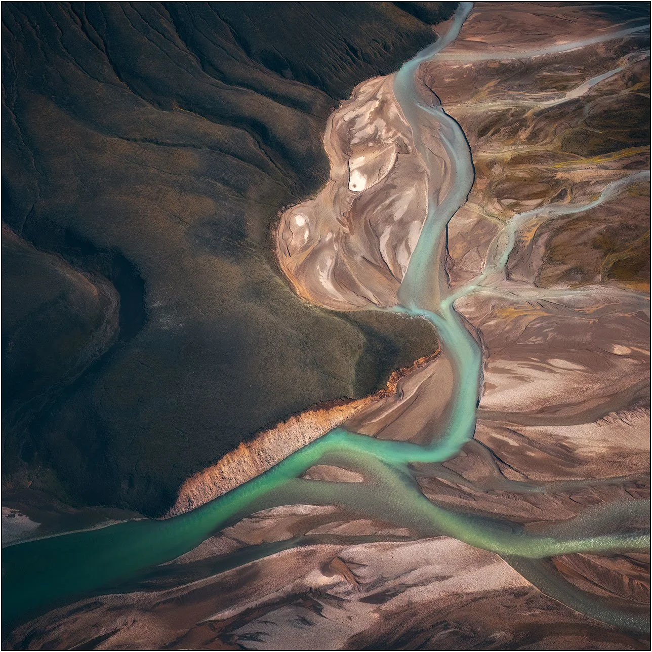 Aerial view of branching glacial rivers carving abstract patterns.
