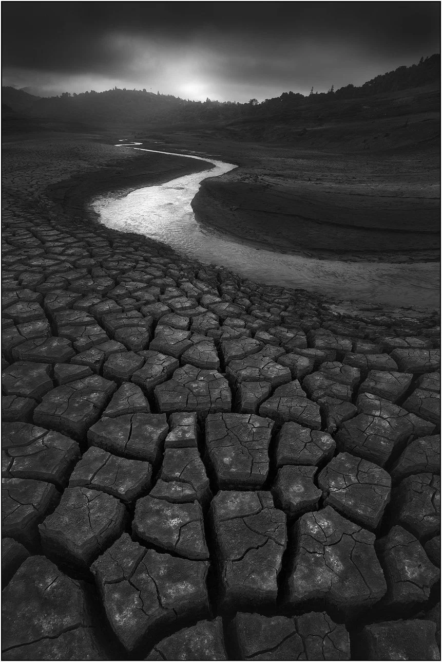 Dry riverbed with cracked mud patterns and winding water channel