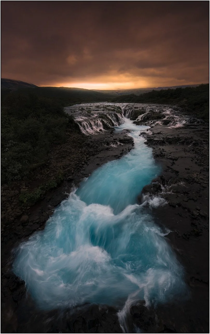 Sunset at Bruarfoss, Iceland, with golden sky and blue waterfall.
