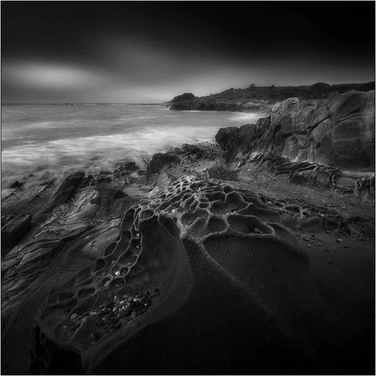 Tafoni coastal rocks under a dark minimalist sky (black and white)